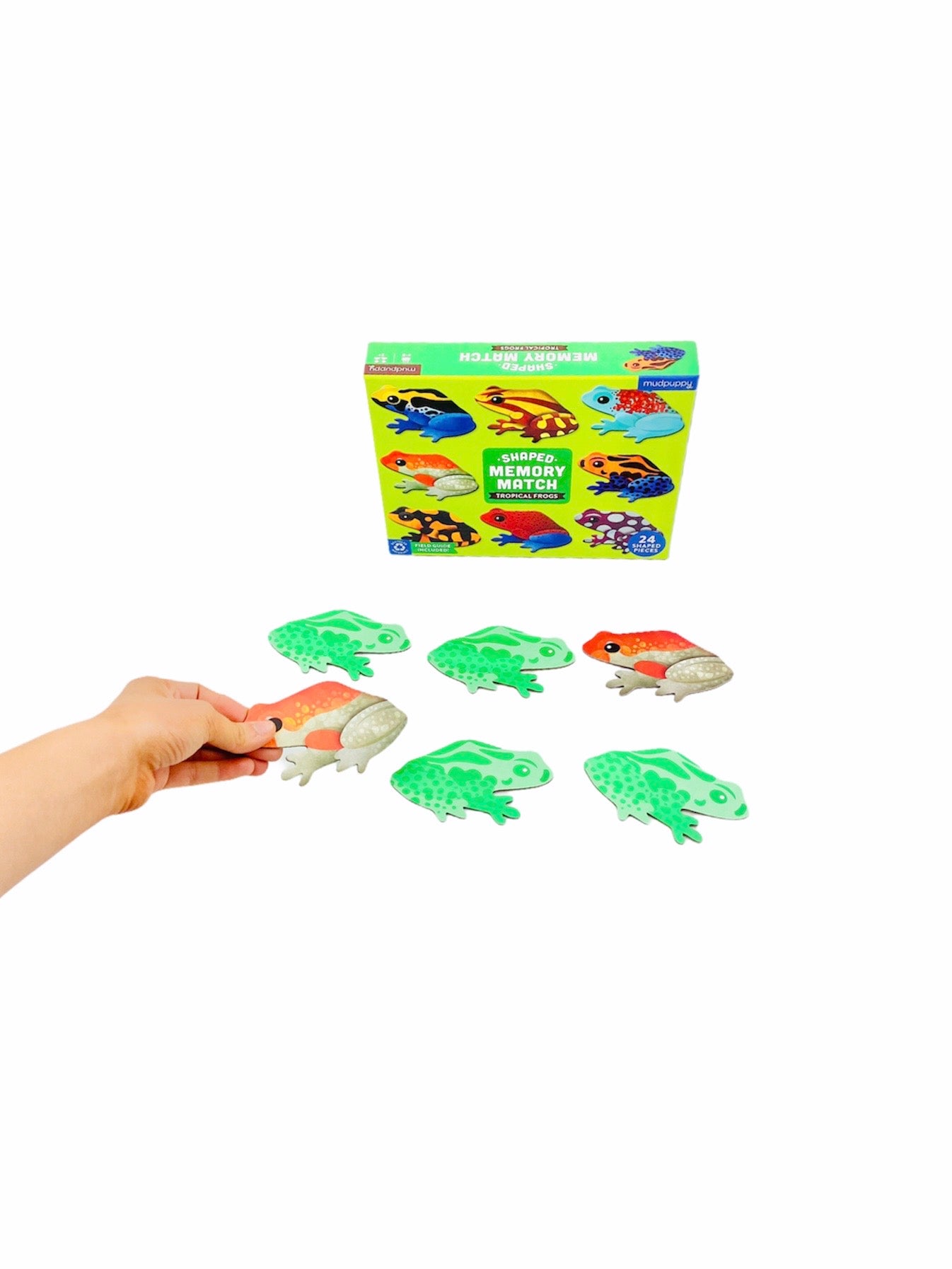 the MudPuppy Tropical Frogs Shaped Memory Match on display with a hand holding one of the tropical frogs