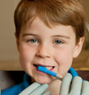 a young boy brushing his teeth with the blue ark brush tip