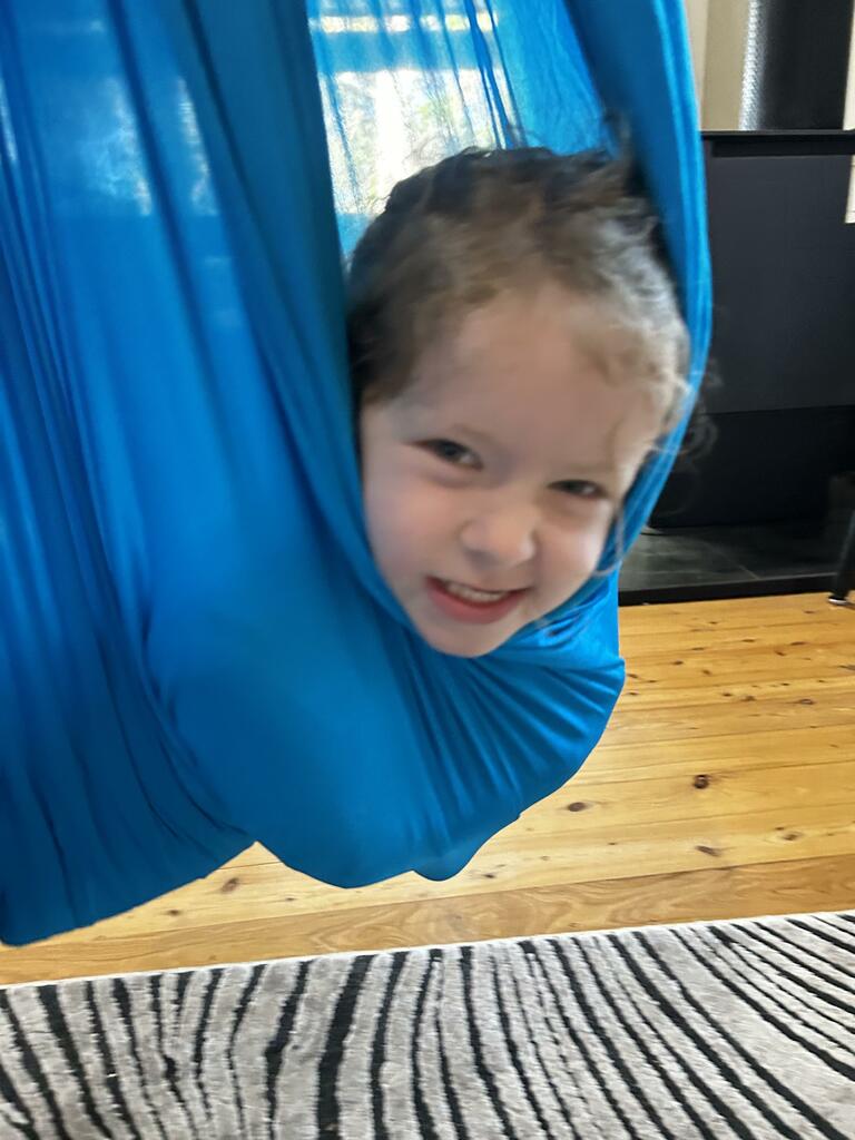 a young child swinging in the harkla compression sensory swing