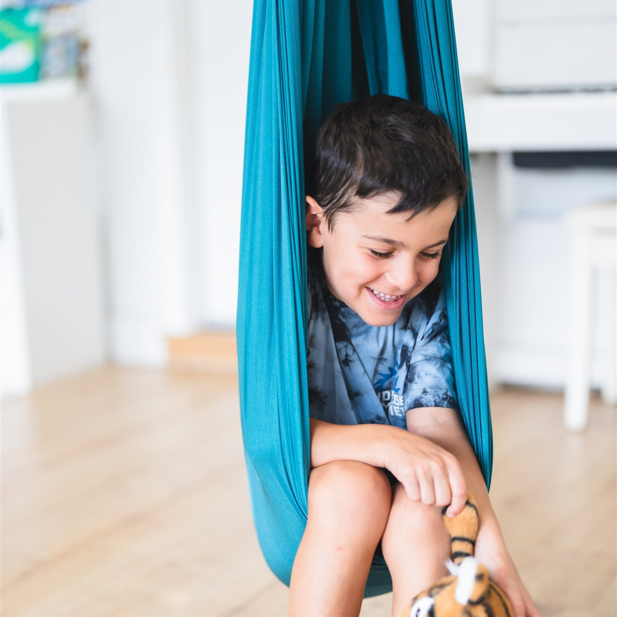 A young boy sitting in the Deluxe Compression Sensory Swing
