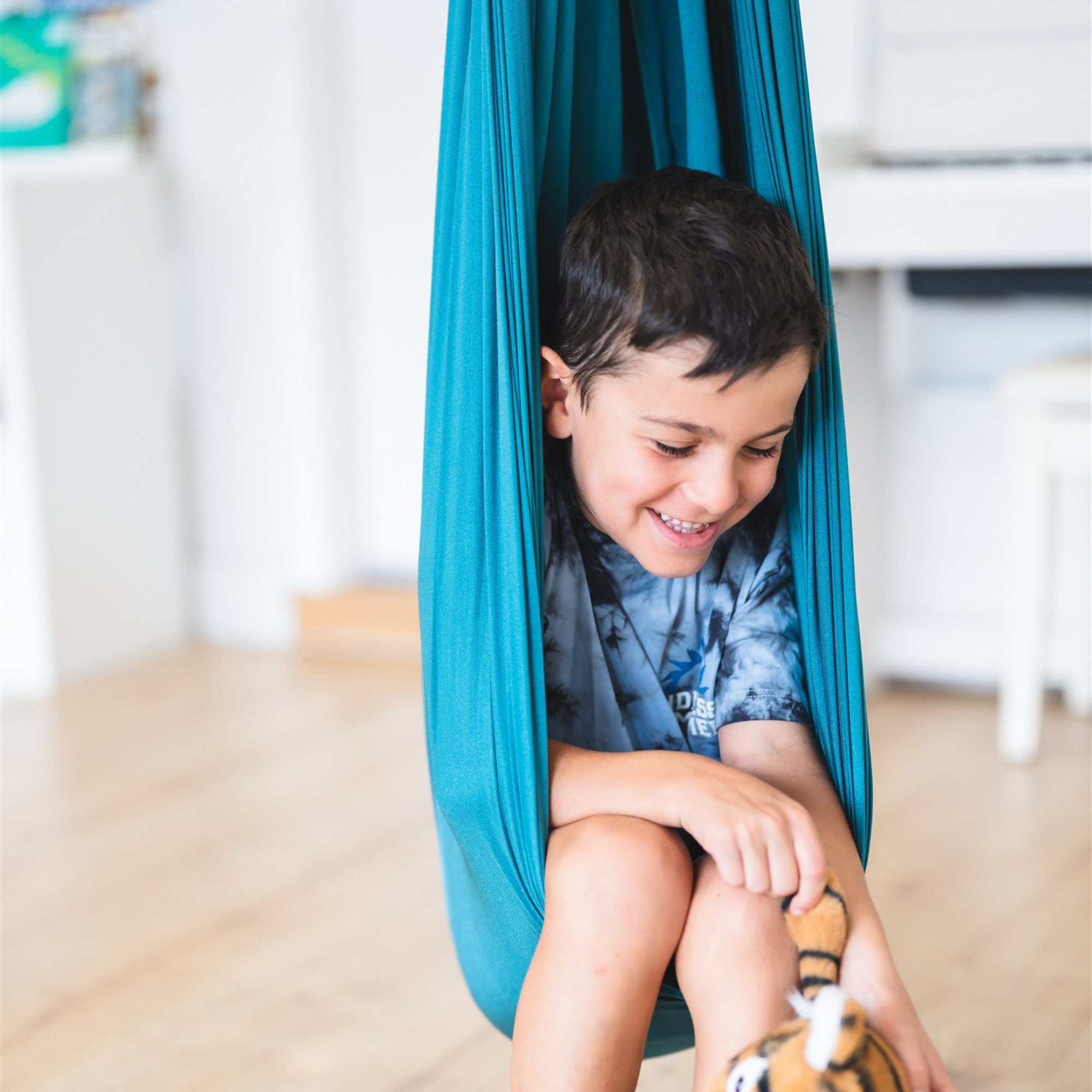 A young boy sitting in the Deluxe Compression Sensory Swing