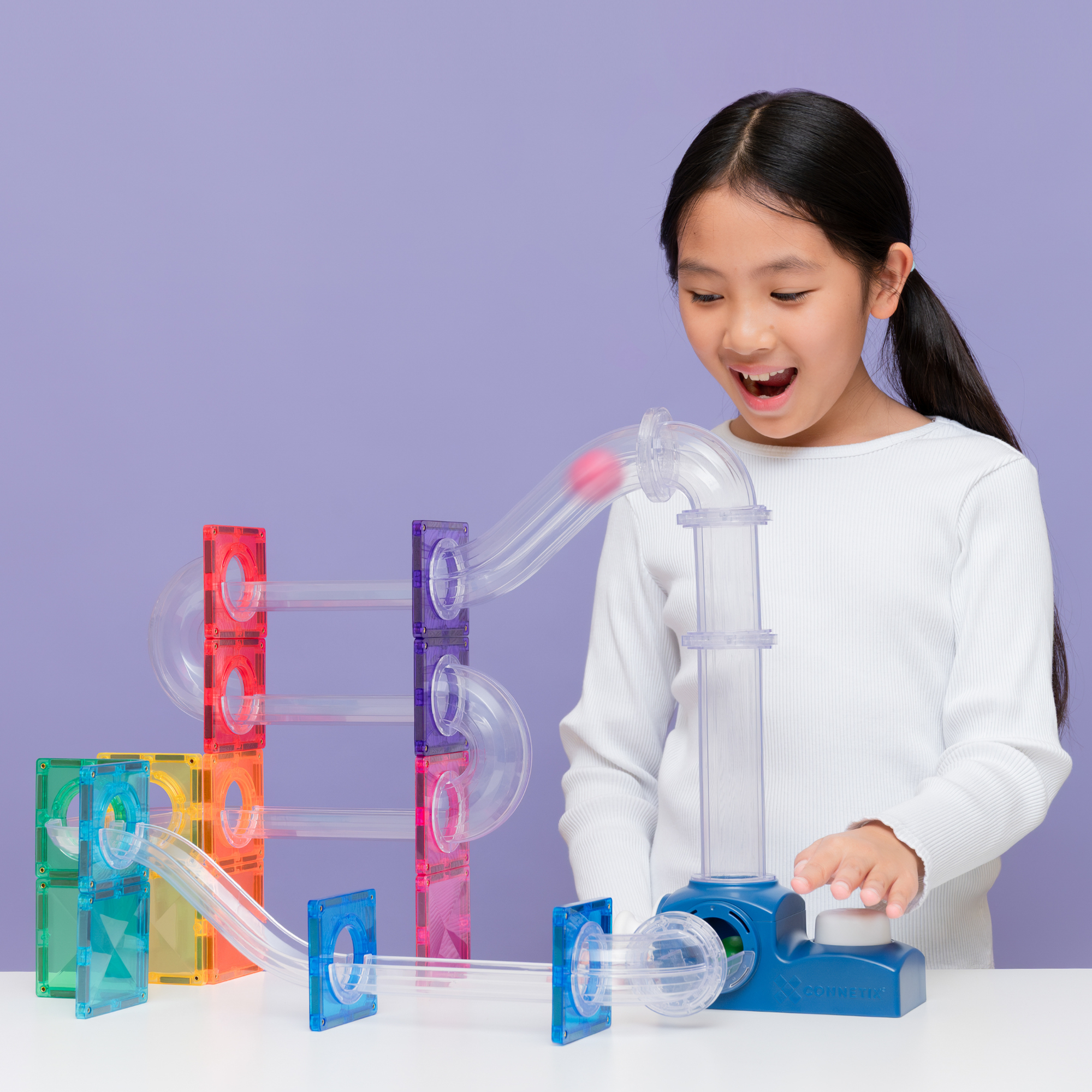 A young girl playing with the Connetix Ball Run - Launcher Pack 47pc