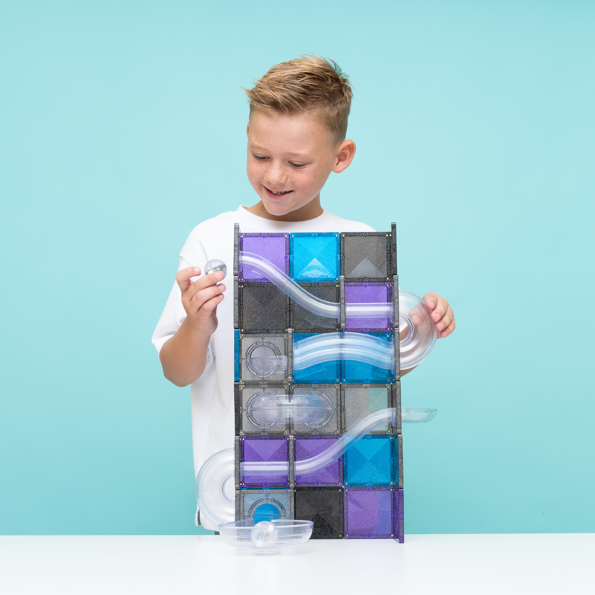 A young boy playing with the Connetix Ball Run - Galaxy Pack 61pc