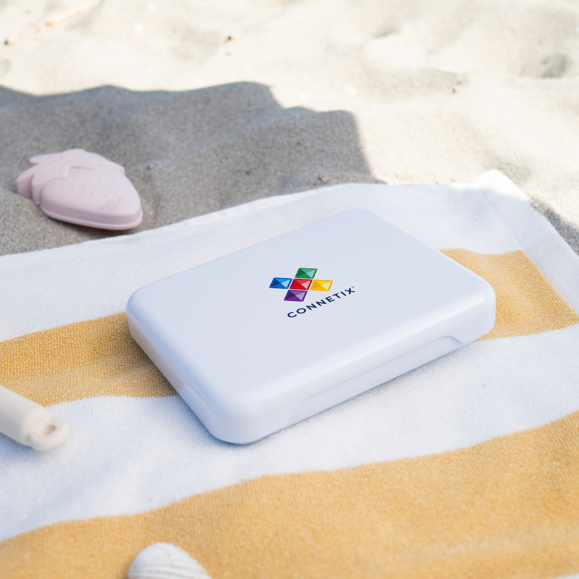 The Connetix Tiles - Travel Mini Pack 32pc pictured on a white and yellow towel on the beach