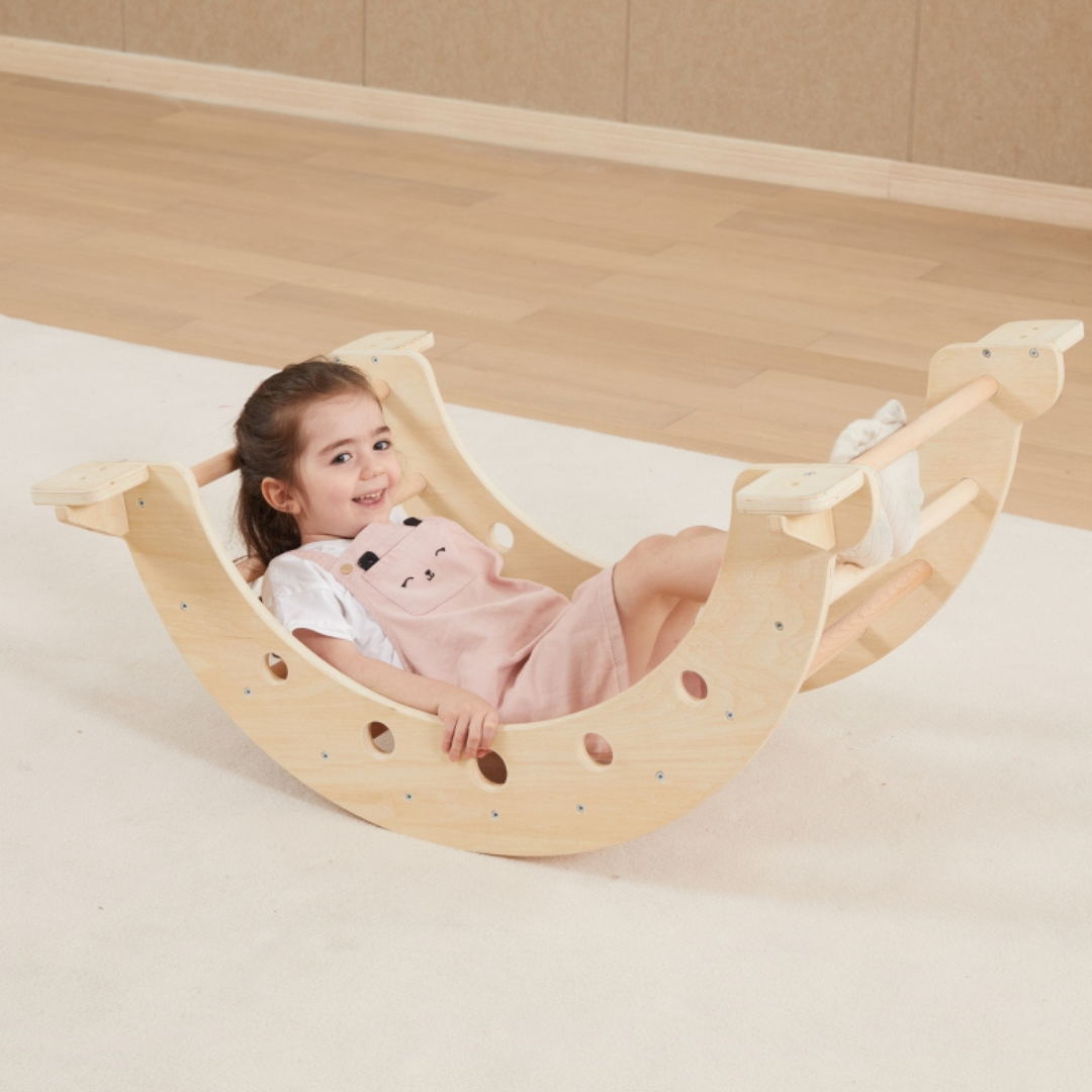 A young girl rocking in the VIGA Wooden Climbing Arch