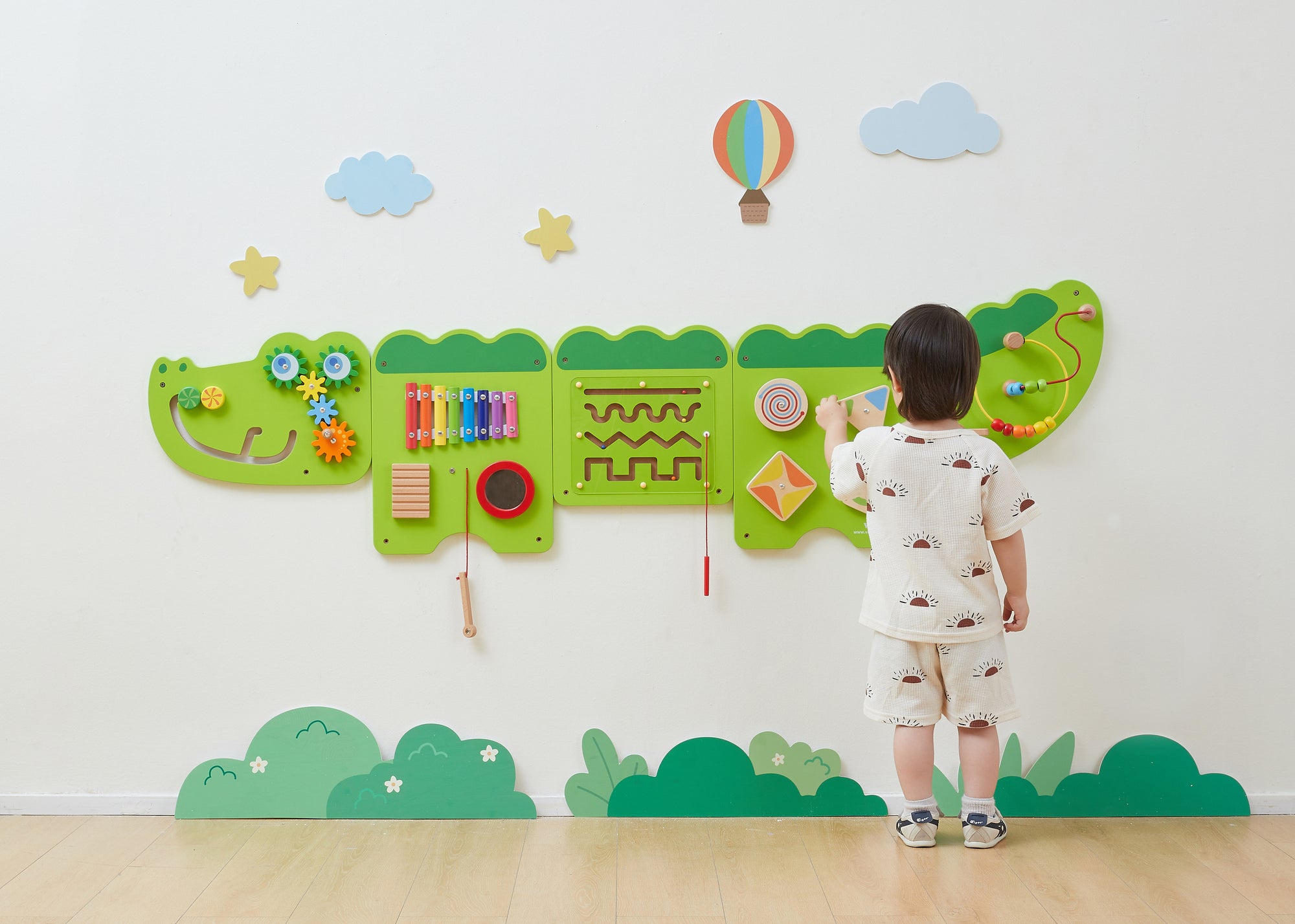 A young boy playing with the VIGA Interactive Wall Mural Junior Crocodile mounted on a wall