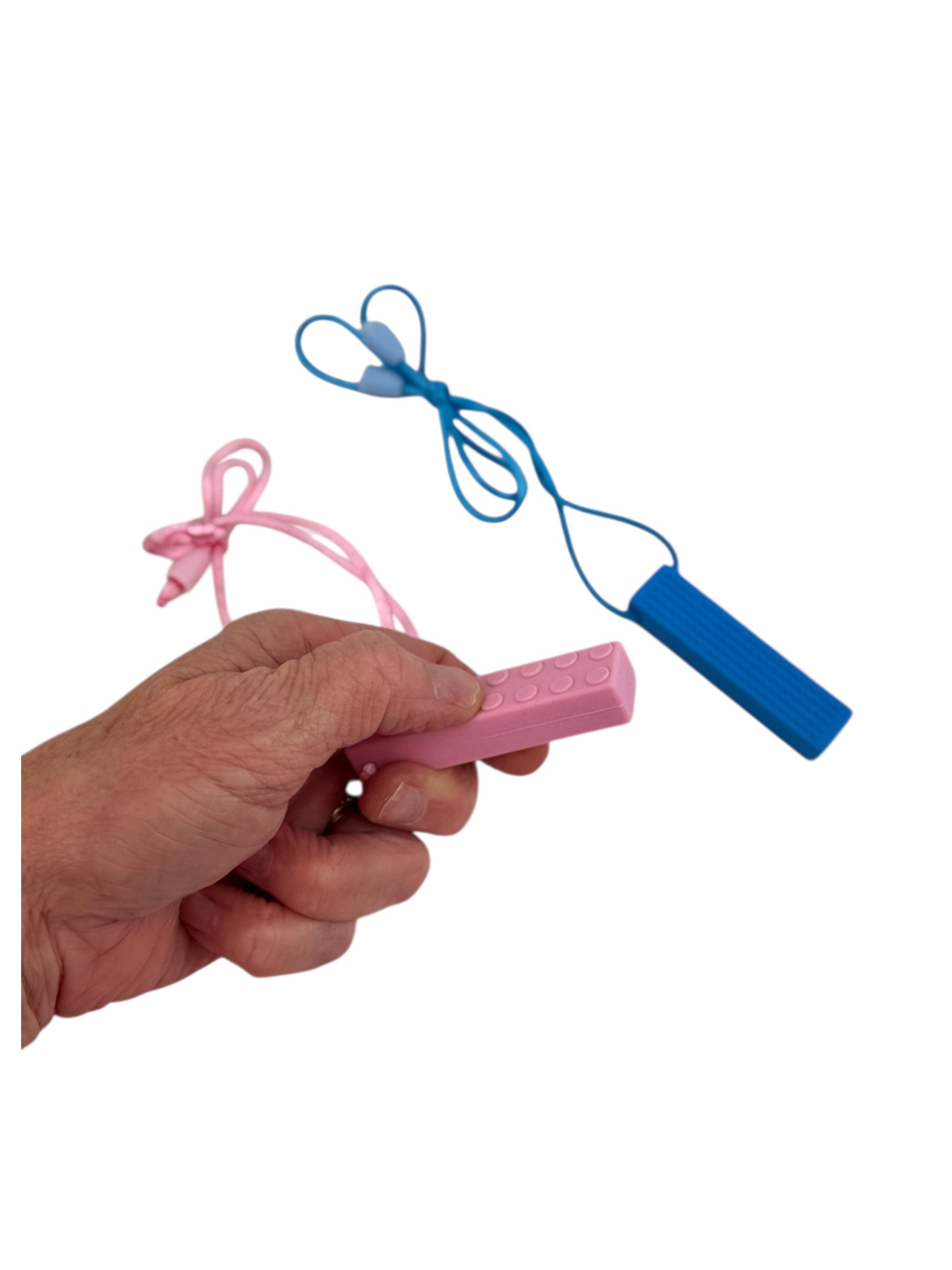 a hand holding the pink Chewy Charms Necklace Chew - Brick with the blue brick in the background