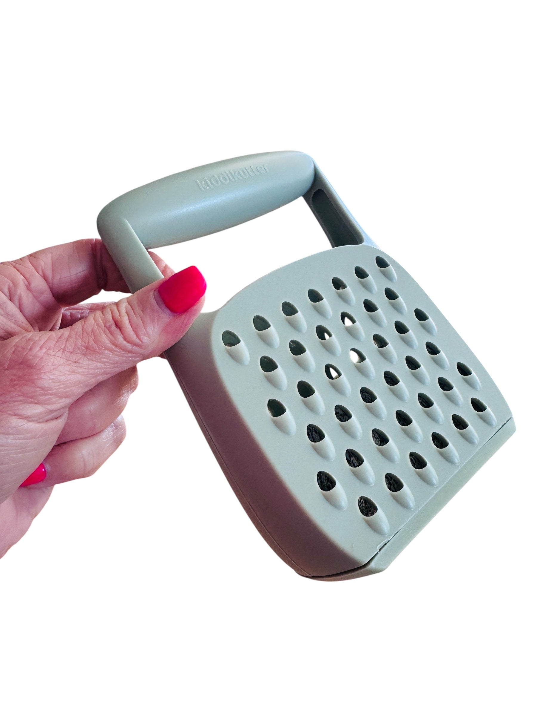 A hand holding the Kiddikutter Safety Grater pictured on a white background