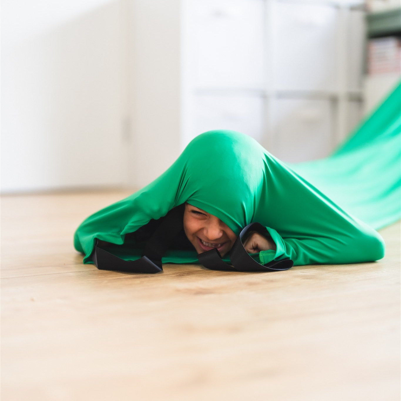 a boy crawling through the green Deluxe Lycra Compression Tunnel