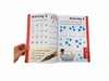 a hand turning the page on the Phonics Workbook - Phase 3
