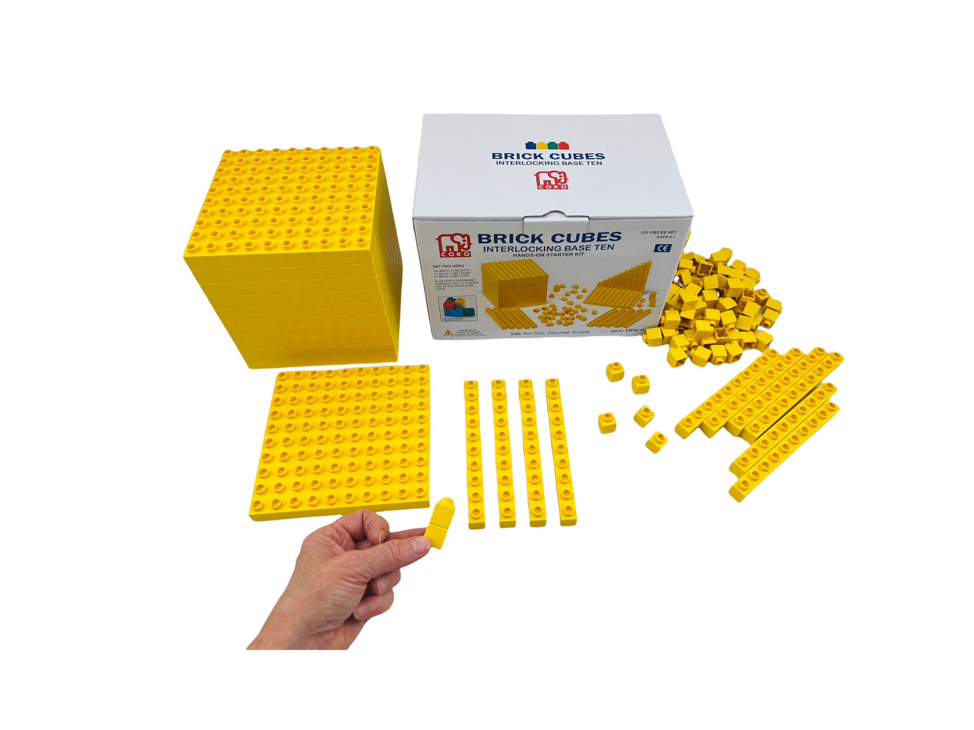 a hand holding a piece from the Coko Brick Cubes Interlocking Base Ten set in front of the rest of the Coko Brick Cubes Interlocking Base Ten set