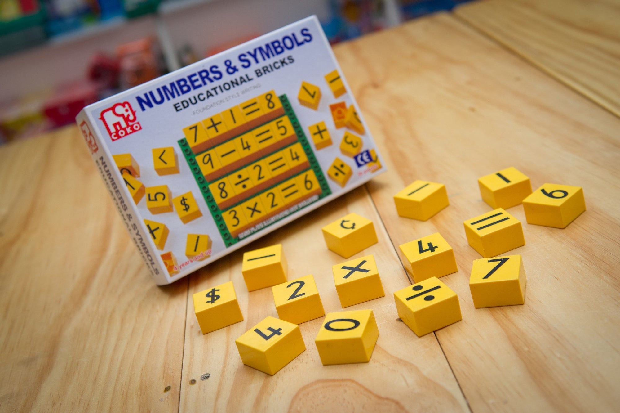 Coko Bricks Numbers &amp; Symbols with bricks laid out with box on wooden table