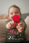 a young girl holding out the red plain Chew Stixx Chew Lolli Knobby