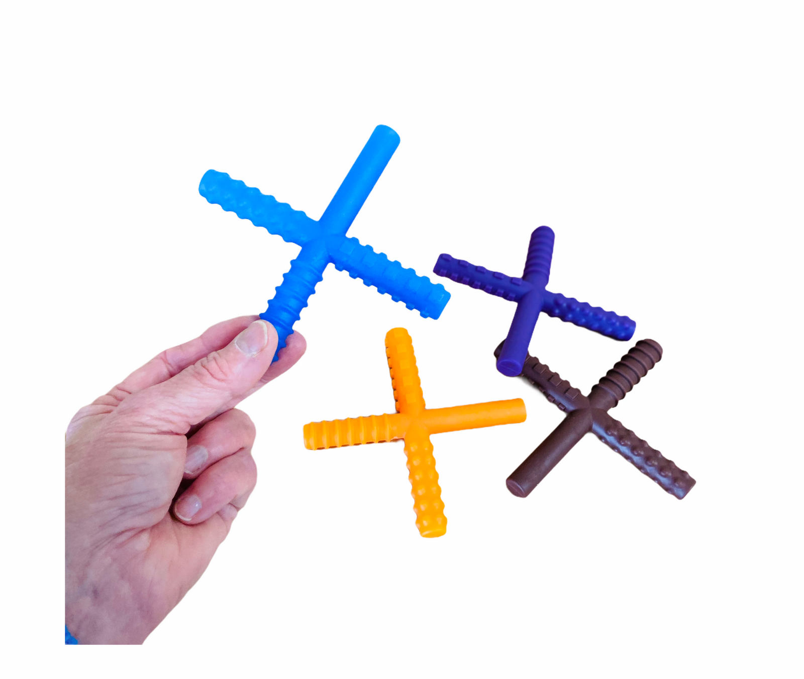 hand holding the Chew Stixx blue and a orange, brown and blue chew stixx in the background