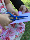 a little child cutting through paper with the Spring back Scissors