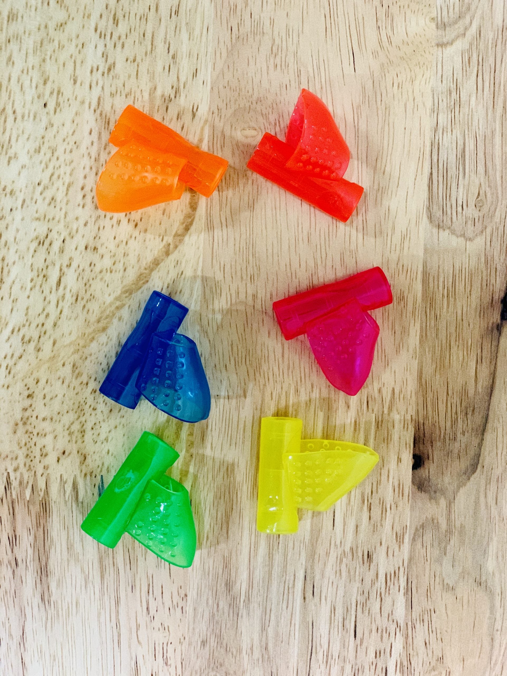 orange, red, blue, pink, green and yellow Pencil Grip Pointer Grips on wooden table
