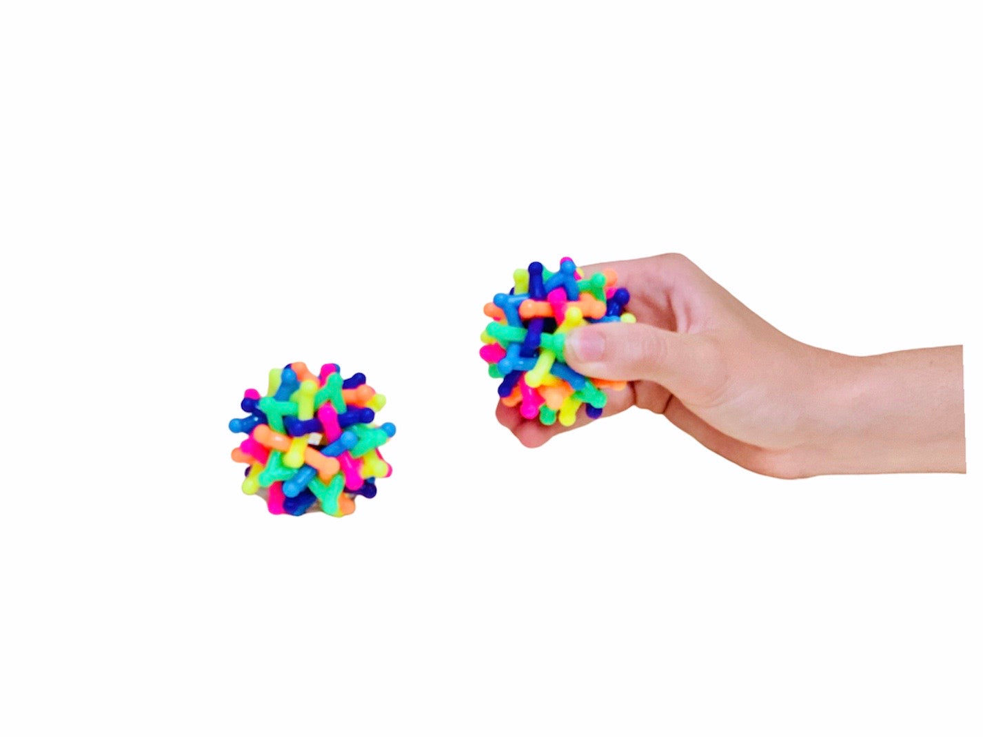 a hand holding a Knitting Stress Ball and on sitting directly next to it