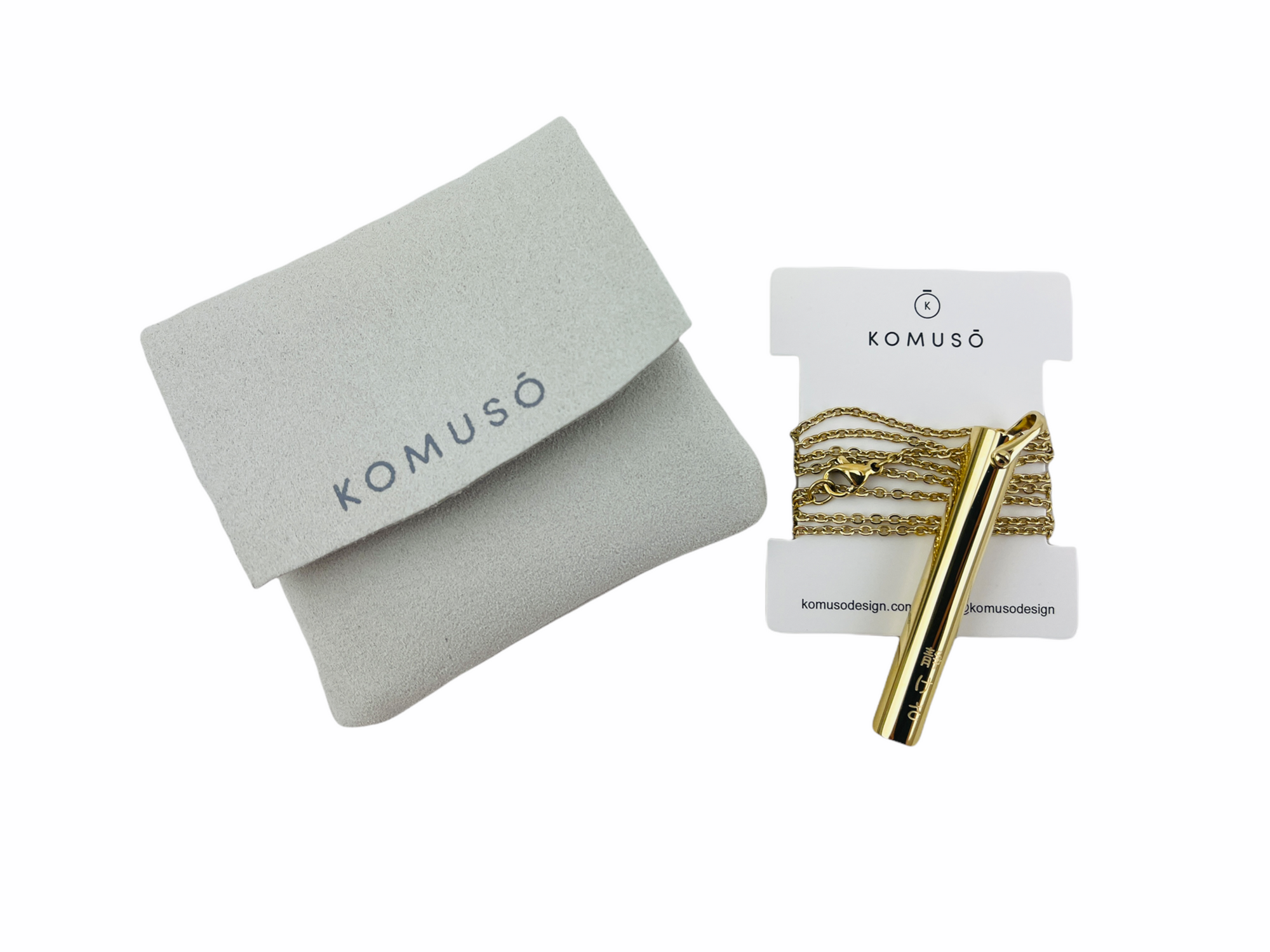 Komuso Shift Necklace - Gold laid next to packaging on white background