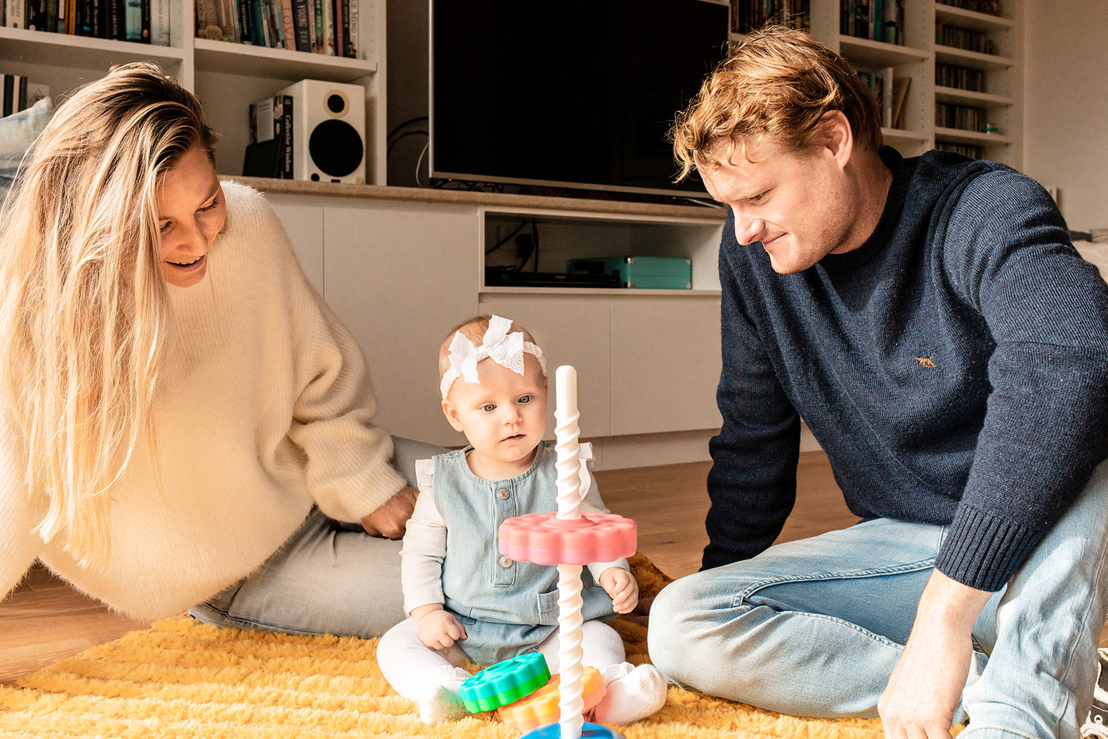 a baby girl and 2 adults playing the Fat Brain Spin Again