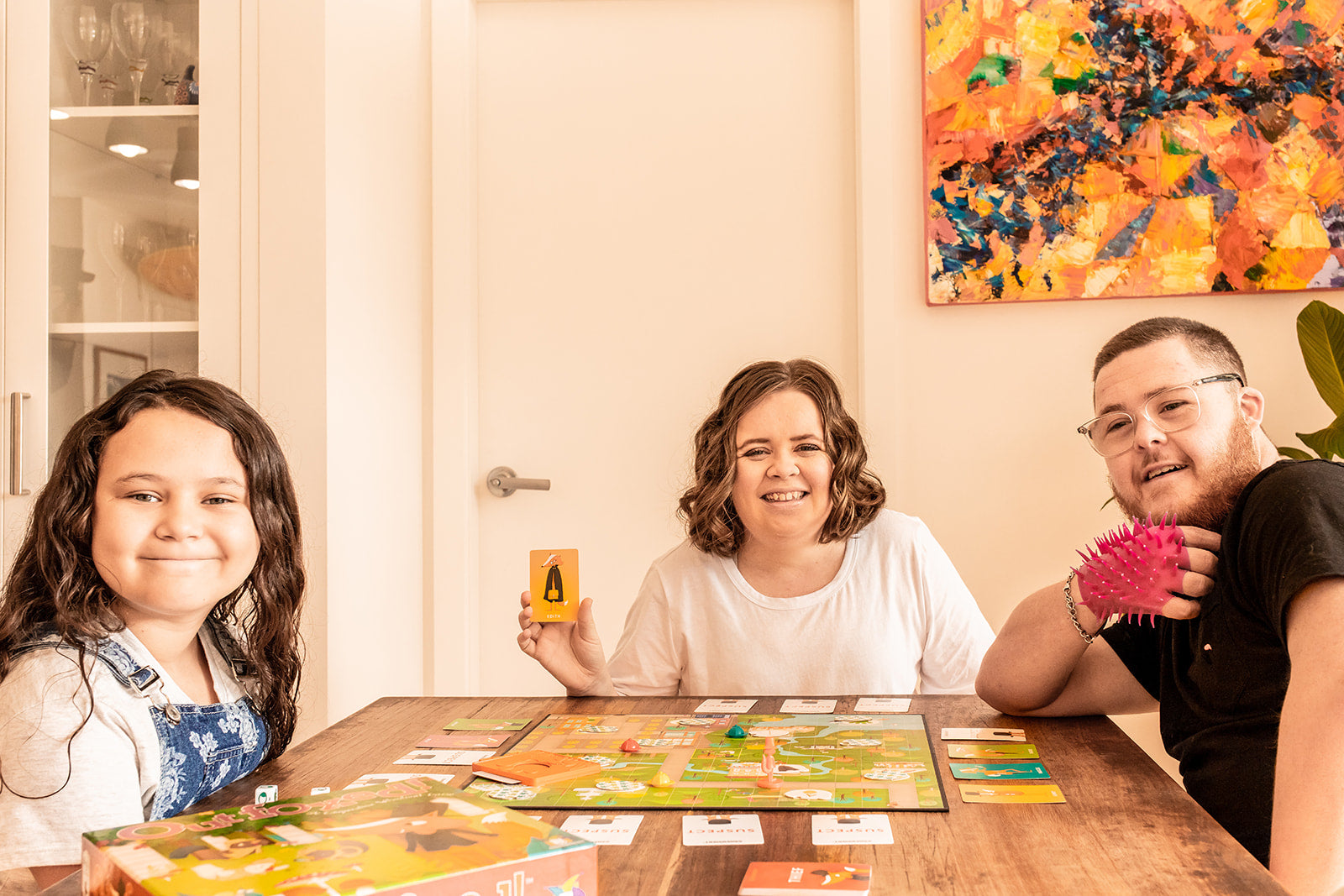 2 girls and a boy playing Gamewright Outfoxed on a wooden table