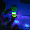 a child playing the green Glo Pals Light-Up Cubes in the bath